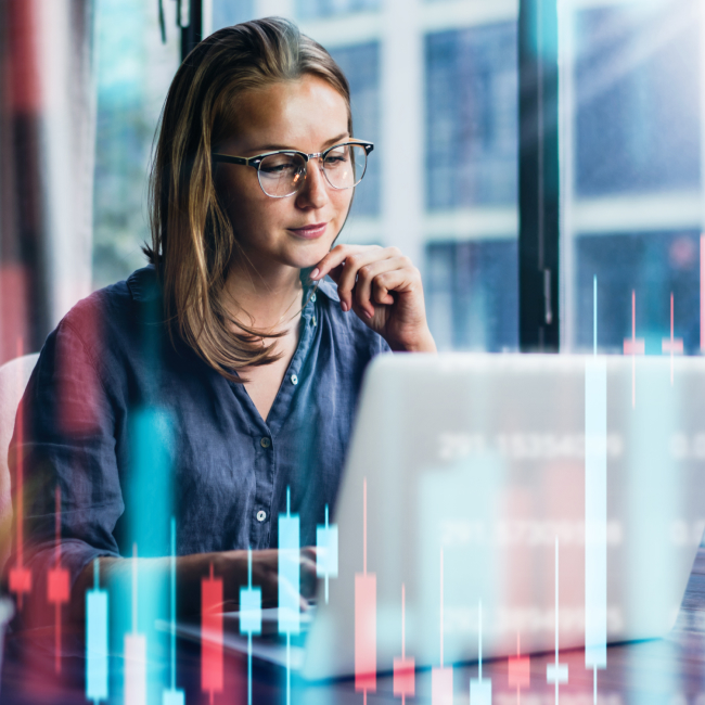 Una donna con gli occhiali che studia dati finanziari su un computer portatile.